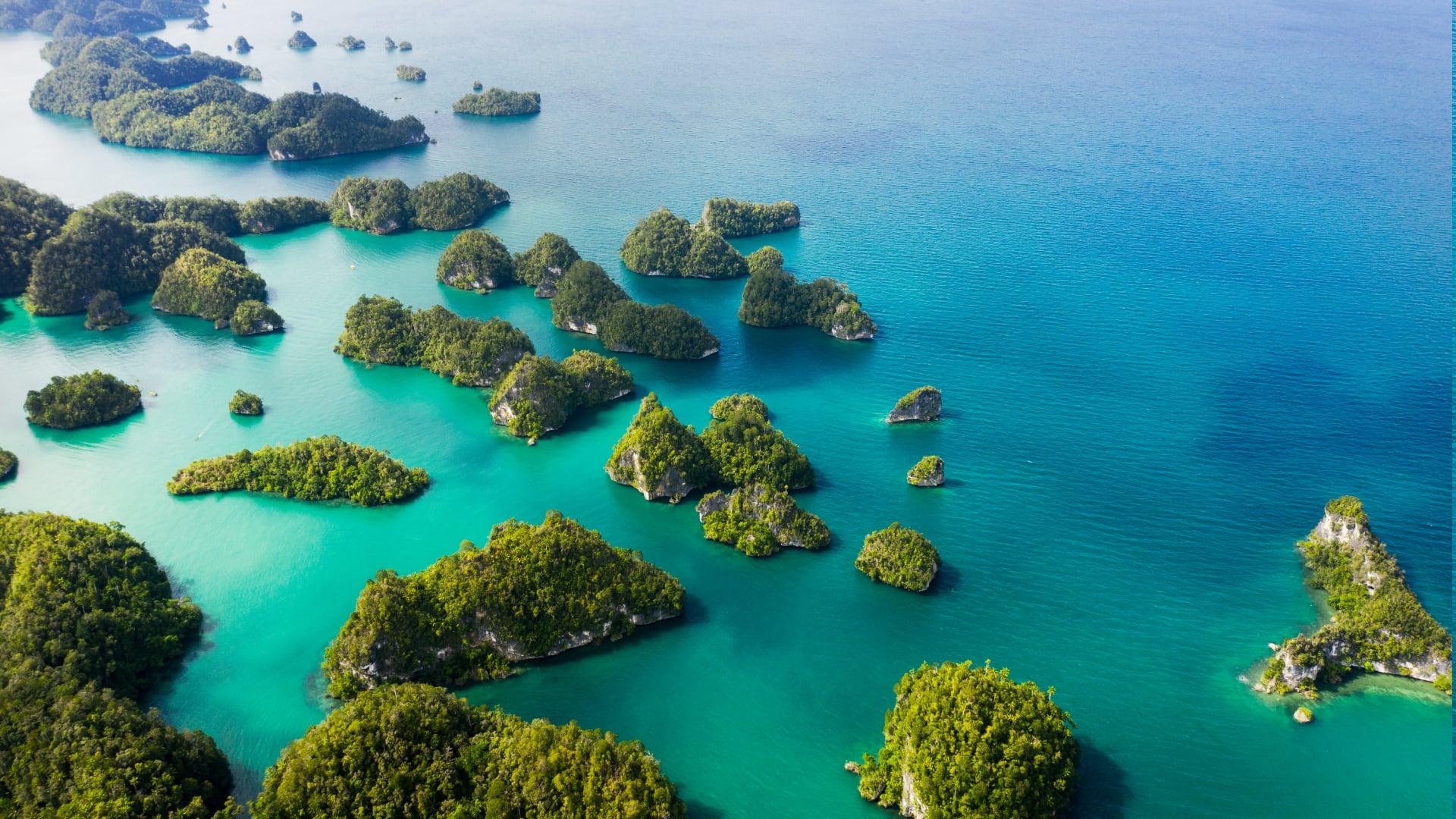 Aerial view of lush green islets in a vibrant blue sea in Indonesia.
