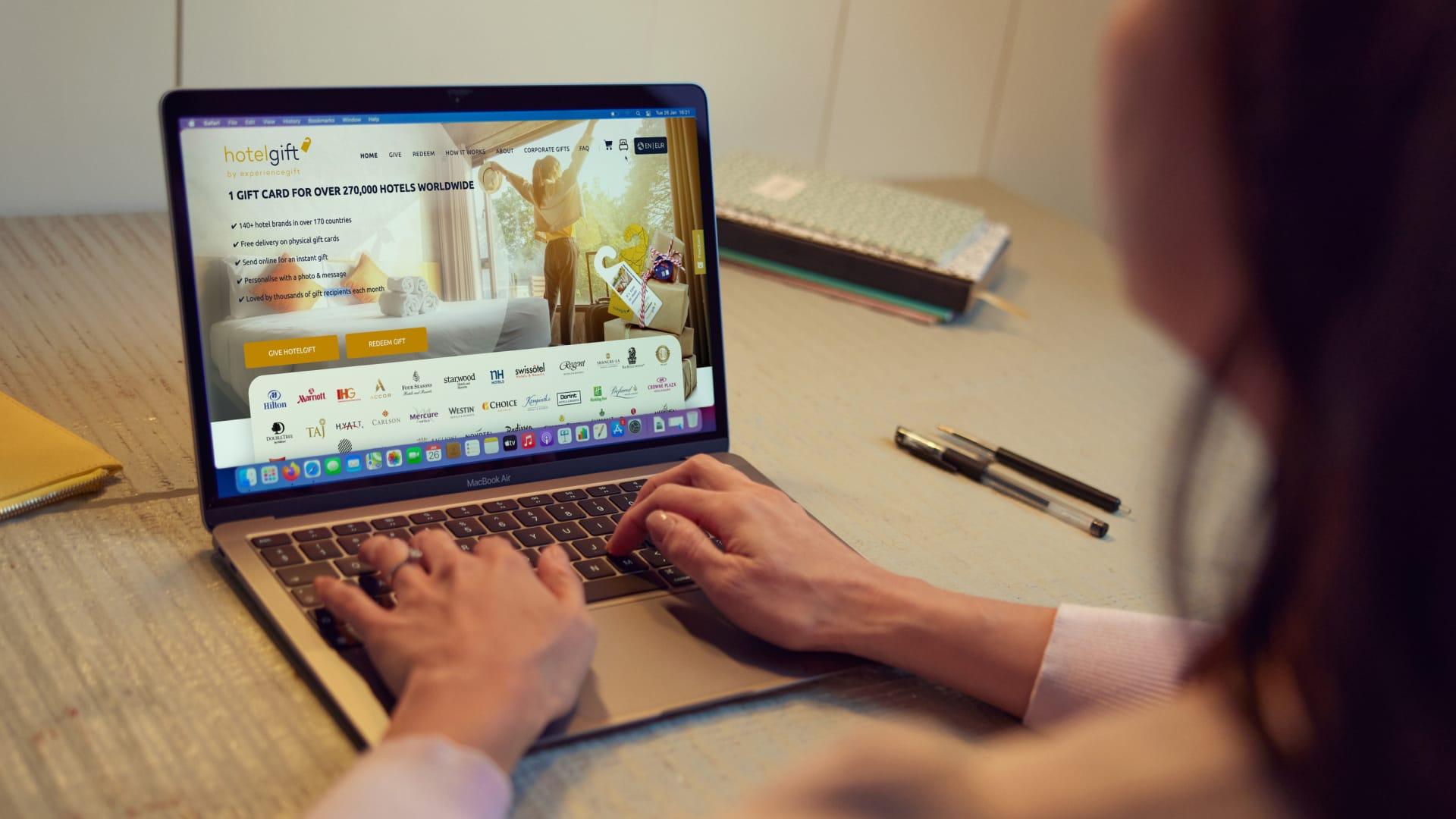 Persoon die een laptop gebruikt met de website Hotel Gift met diverse hotelmerklogo's